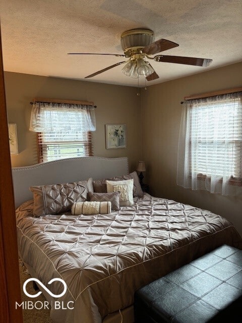 bedroom with ceiling fan and a textured ceiling