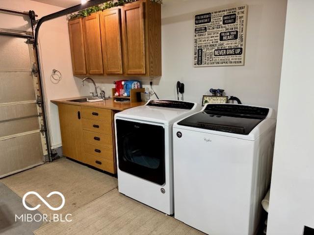 washroom with cabinets, washing machine and dryer, and sink