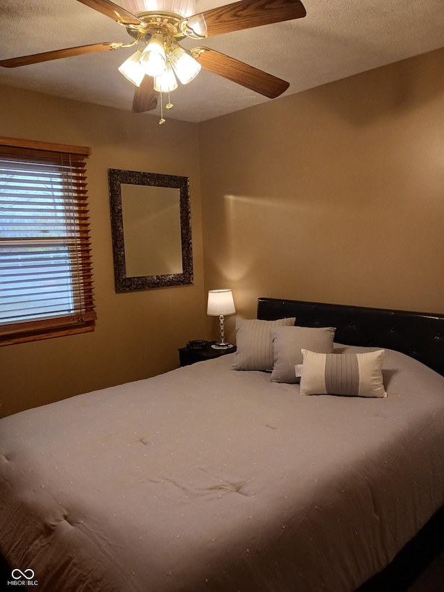 bedroom with ceiling fan and a textured ceiling