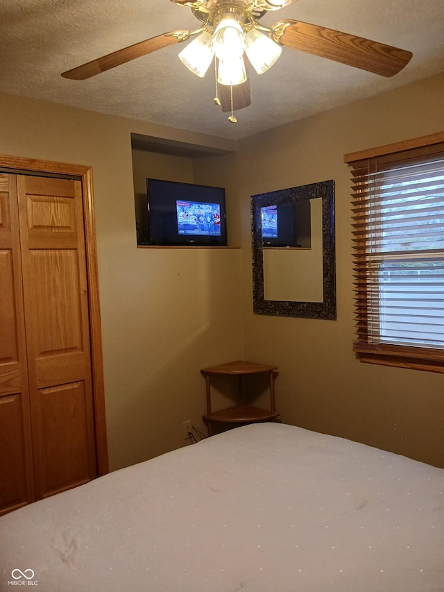 unfurnished bedroom featuring ceiling fan, a closet, and a textured ceiling