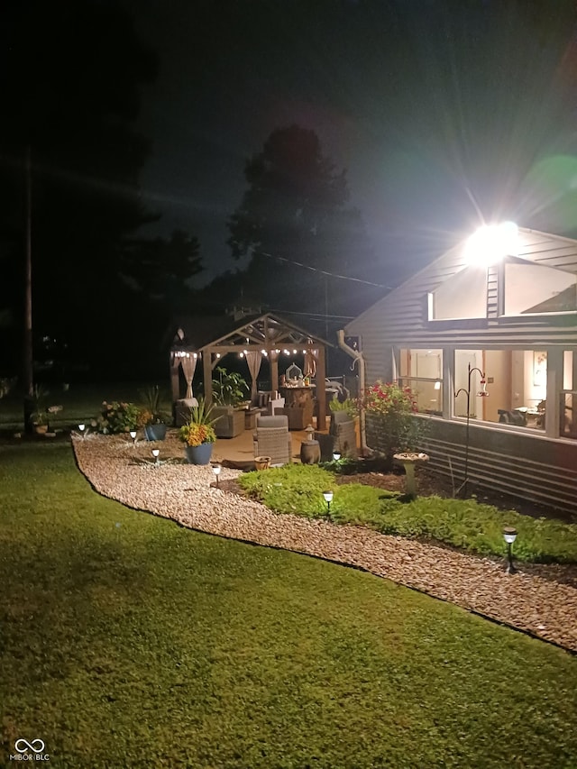 yard at night with an outdoor living space and a gazebo