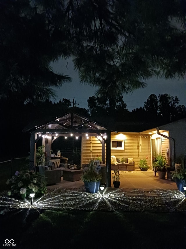 back house at twilight with a gazebo, outdoor lounge area, a shed, and a patio area