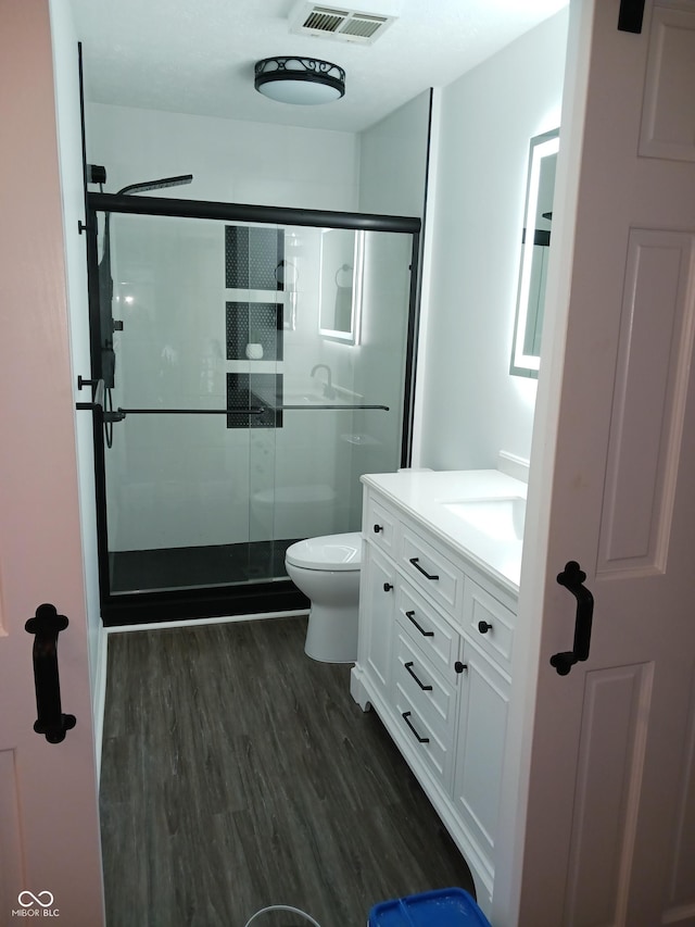 bathroom with walk in shower, hardwood / wood-style floors, vanity, and toilet