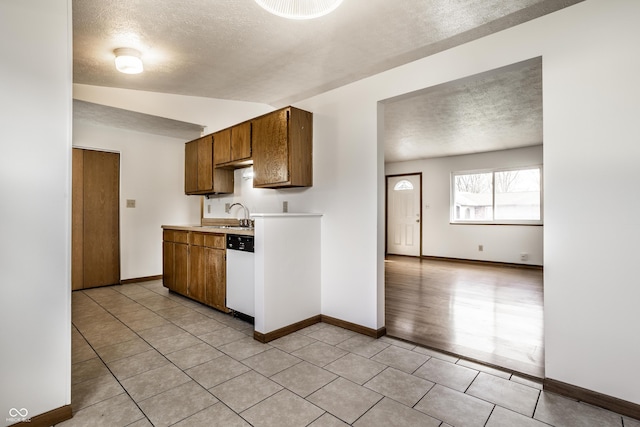 kitchen featuring dishwasher, a textured ceiling, lofted ceiling, and sink