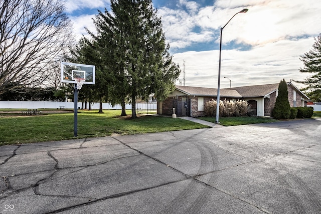 exterior space with basketball hoop and a front yard