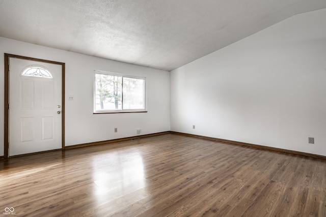 entryway with hardwood / wood-style flooring, lofted ceiling, and a textured ceiling