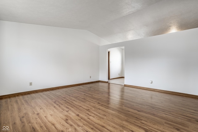 spare room featuring wood-type flooring, a textured ceiling, and vaulted ceiling