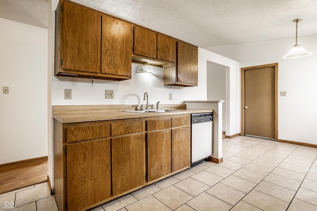 kitchen with white dishwasher, sink, hanging light fixtures, and a textured ceiling