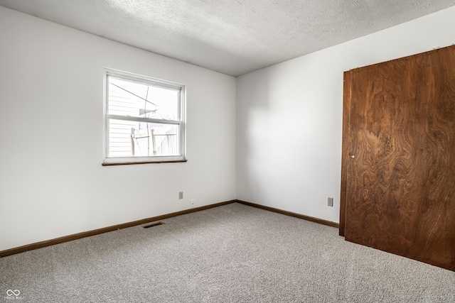 unfurnished room with carpet flooring and a textured ceiling