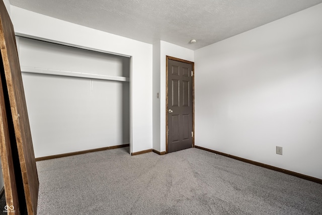 unfurnished bedroom featuring a textured ceiling, light colored carpet, and a closet