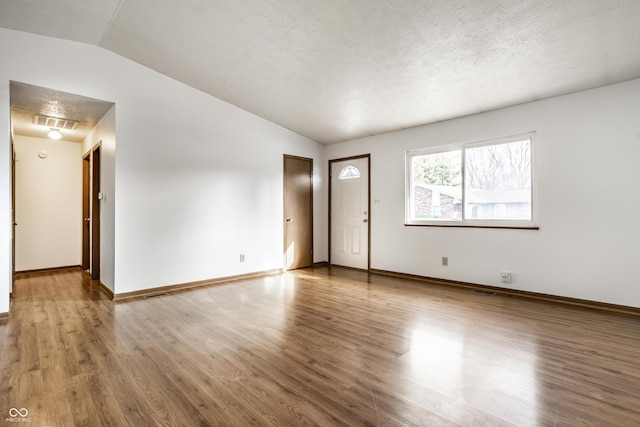 unfurnished room with wood-type flooring, a textured ceiling, and vaulted ceiling