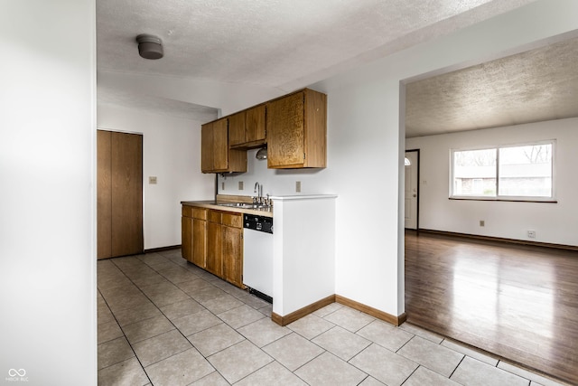 8016 Minlo Dr, Indianapolis, IN 46227 - kitchen featuring white dishwasher, a textured ceiling, light tile patterned flooring, light countertops, and brown cabinetry