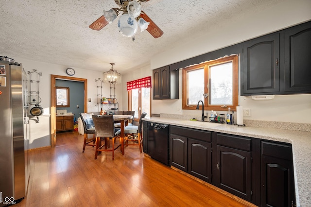 kitchen with sink, stainless steel refrigerator, dishwasher, hanging light fixtures, and light hardwood / wood-style floors