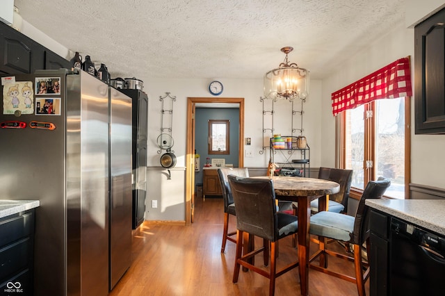 dining area with a notable chandelier, light hardwood / wood-style flooring, and a textured ceiling