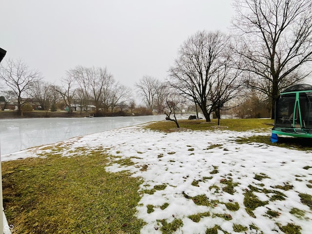 yard layered in snow featuring a water view and a trampoline