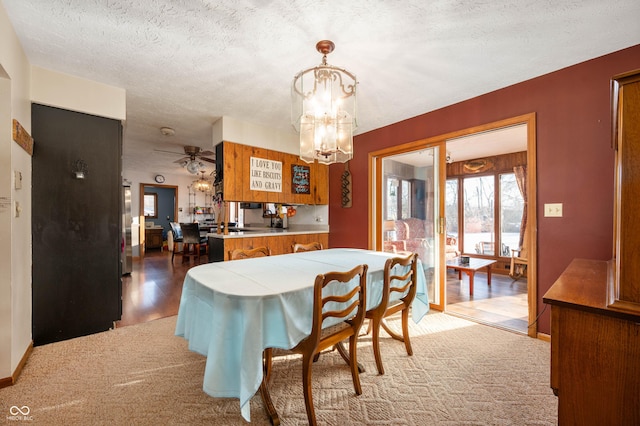 carpeted dining room with an inviting chandelier and a textured ceiling