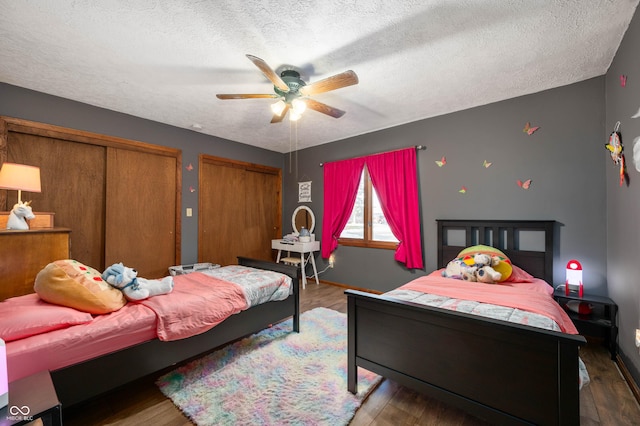 bedroom with dark hardwood / wood-style flooring, two closets, and a textured ceiling