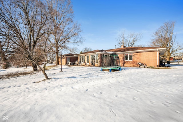 snow covered rear of property featuring a trampoline