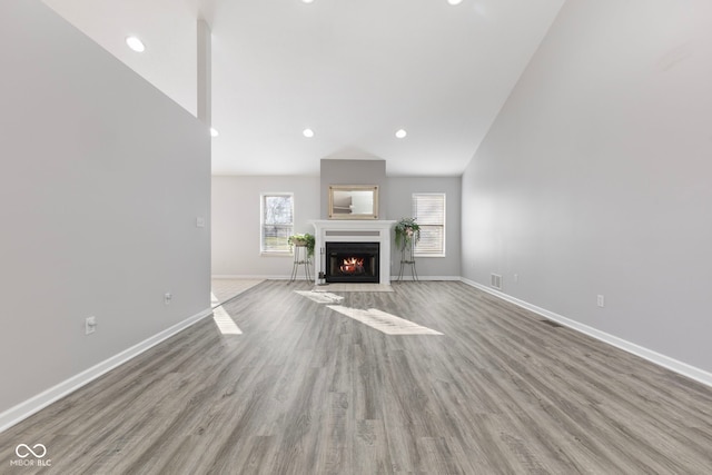 2395 W Robin Rd, Scottsburg, IN 47170 - unfurnished living room with wood finished floors, a fireplace with flush hearth, recessed lighting, and lofted ceiling