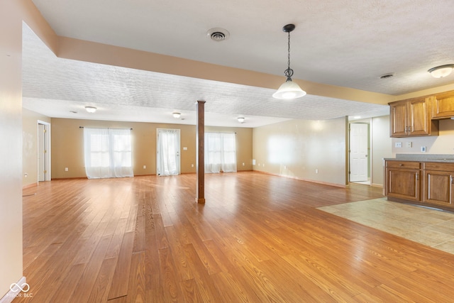 unfurnished living room featuring light hardwood / wood-style flooring and a textured ceiling