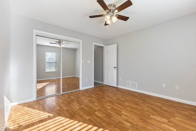 unfurnished bedroom featuring ceiling fan, a closet, and hardwood / wood-style flooring