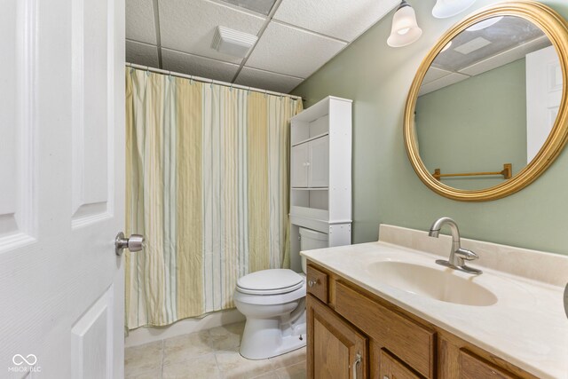 bathroom with a drop ceiling, vanity, tile patterned floors, a shower with shower curtain, and toilet