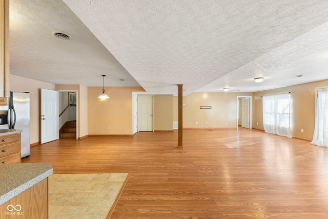 unfurnished living room featuring a textured ceiling and light hardwood / wood-style flooring