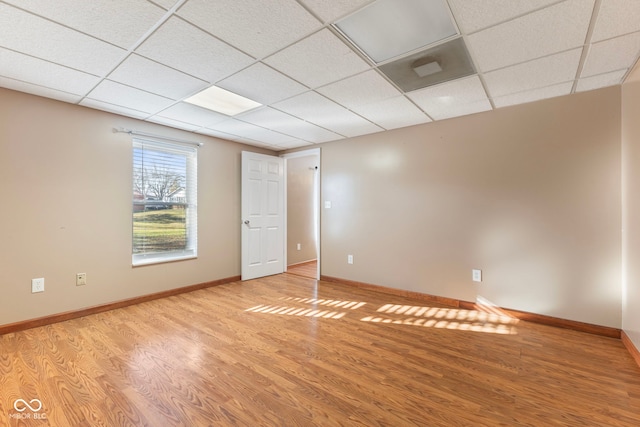 empty room with a paneled ceiling and light hardwood / wood-style floors