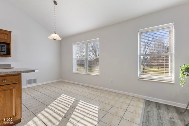 unfurnished dining area featuring light tile patterned floors, lofted ceiling, and a wealth of natural light