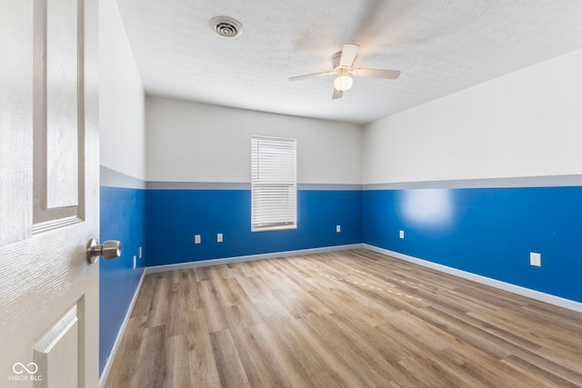 unfurnished room with a textured ceiling, light wood-type flooring, and ceiling fan