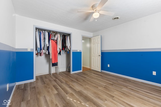 unfurnished bedroom with hardwood / wood-style floors, ceiling fan, a textured ceiling, and a closet