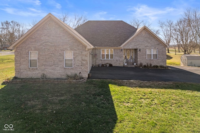 ranch-style house featuring a front yard and a storage unit