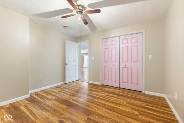 unfurnished bedroom featuring hardwood / wood-style floors, a closet, and ceiling fan