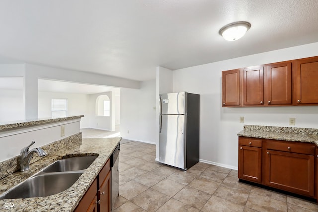 kitchen with stainless steel appliances, light stone counters, and sink