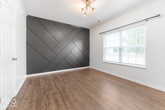 unfurnished room featuring crown molding, an inviting chandelier, and hardwood / wood-style flooring