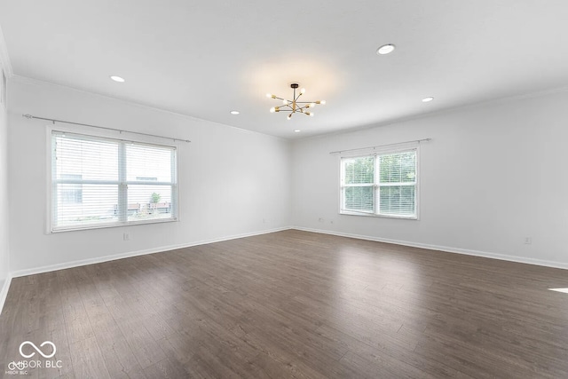 spare room with ornamental molding, dark hardwood / wood-style floors, an inviting chandelier, and a healthy amount of sunlight