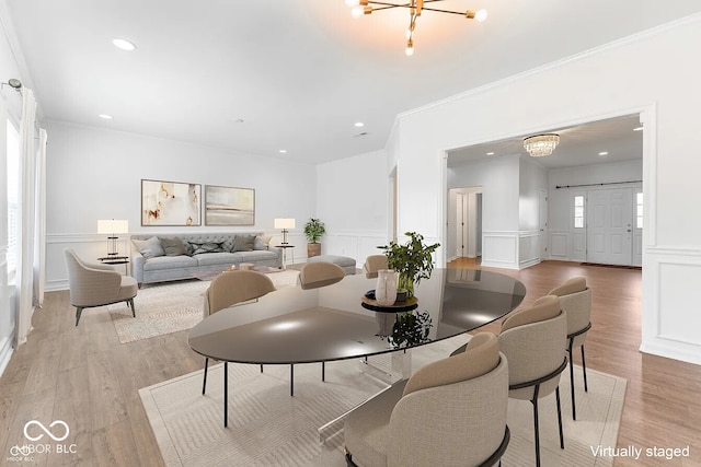 dining space with crown molding, light wood-type flooring, and an inviting chandelier