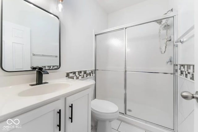 bathroom featuring tile patterned floors, vanity, toilet, and a shower with shower door