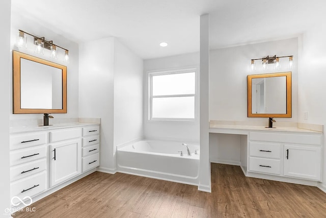 bathroom with a washtub, hardwood / wood-style floors, and vanity