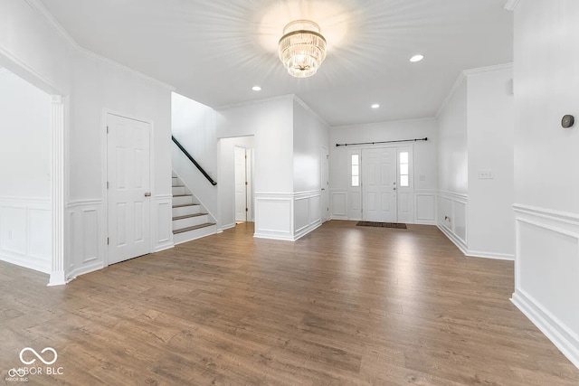 foyer entrance with hardwood / wood-style floors, ornamental molding, and a notable chandelier