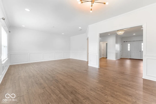 spare room featuring a chandelier, hardwood / wood-style flooring, and crown molding