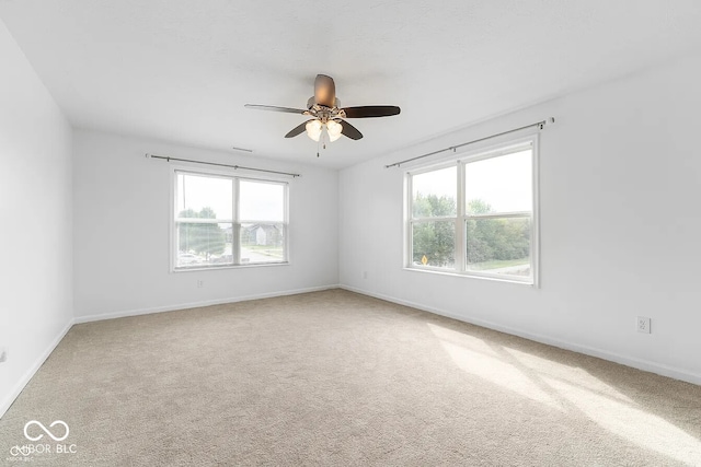 carpeted spare room featuring ceiling fan and a healthy amount of sunlight