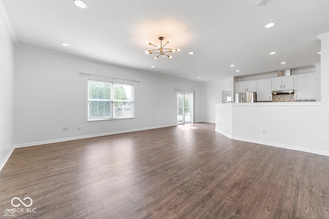 unfurnished living room featuring a notable chandelier, dark hardwood / wood-style floors, and ornamental molding