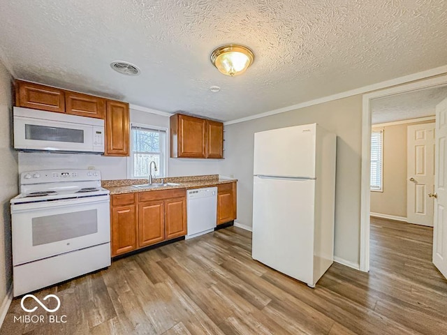 kitchen with white appliances, crown molding, sink, light wood-type flooring, and a textured ceiling