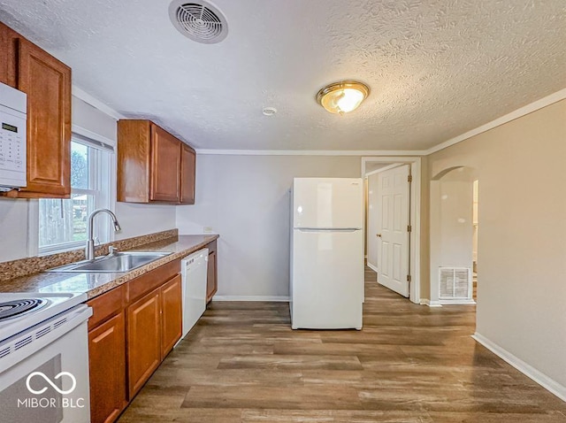 kitchen with ornamental molding, a textured ceiling, white appliances, sink, and dark hardwood / wood-style floors