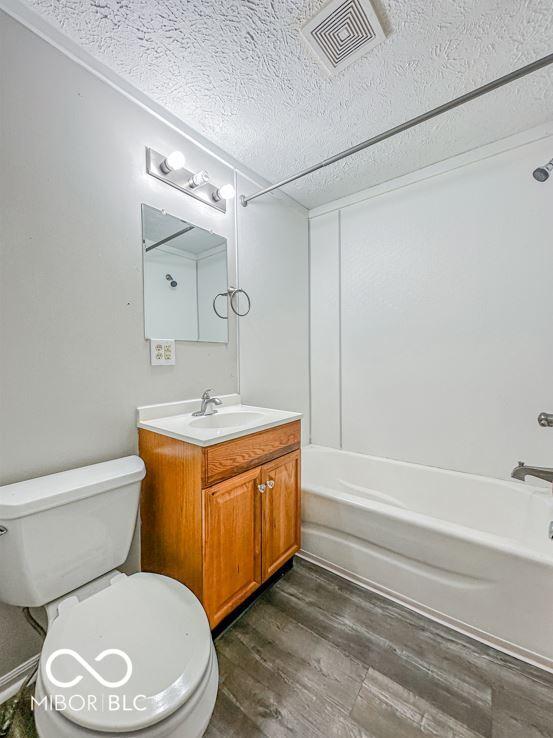 full bathroom featuring vanity, hardwood / wood-style flooring, toilet, and shower / bathtub combination