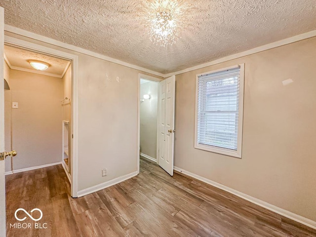 unfurnished bedroom featuring crown molding, wood-type flooring, and a textured ceiling