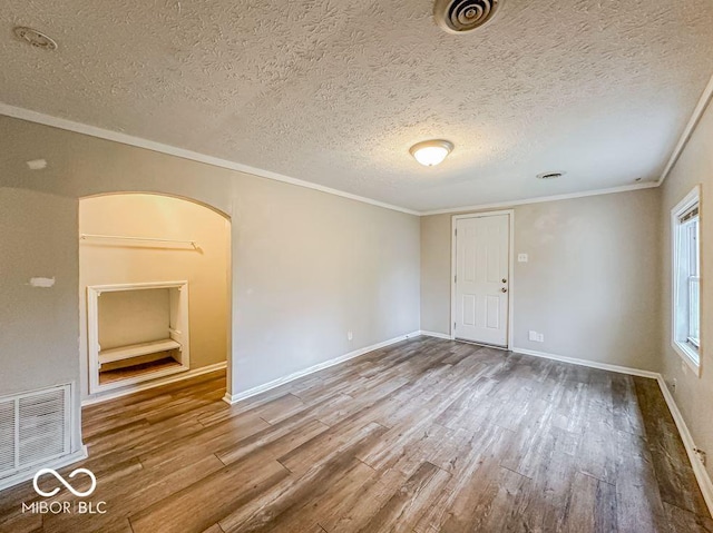 spare room featuring wood-type flooring, a textured ceiling, and ornamental molding