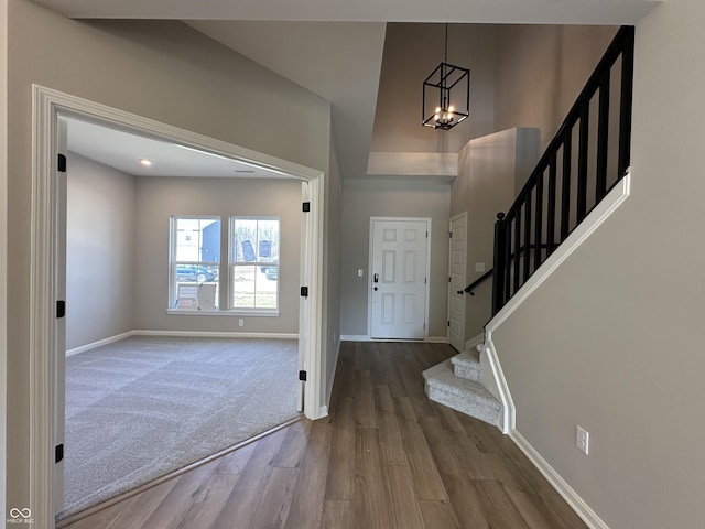 entryway with stairway, baseboards, a notable chandelier, and wood finished floors