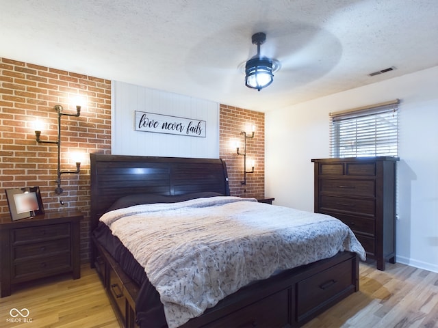 bedroom with ceiling fan, light hardwood / wood-style floors, and a textured ceiling